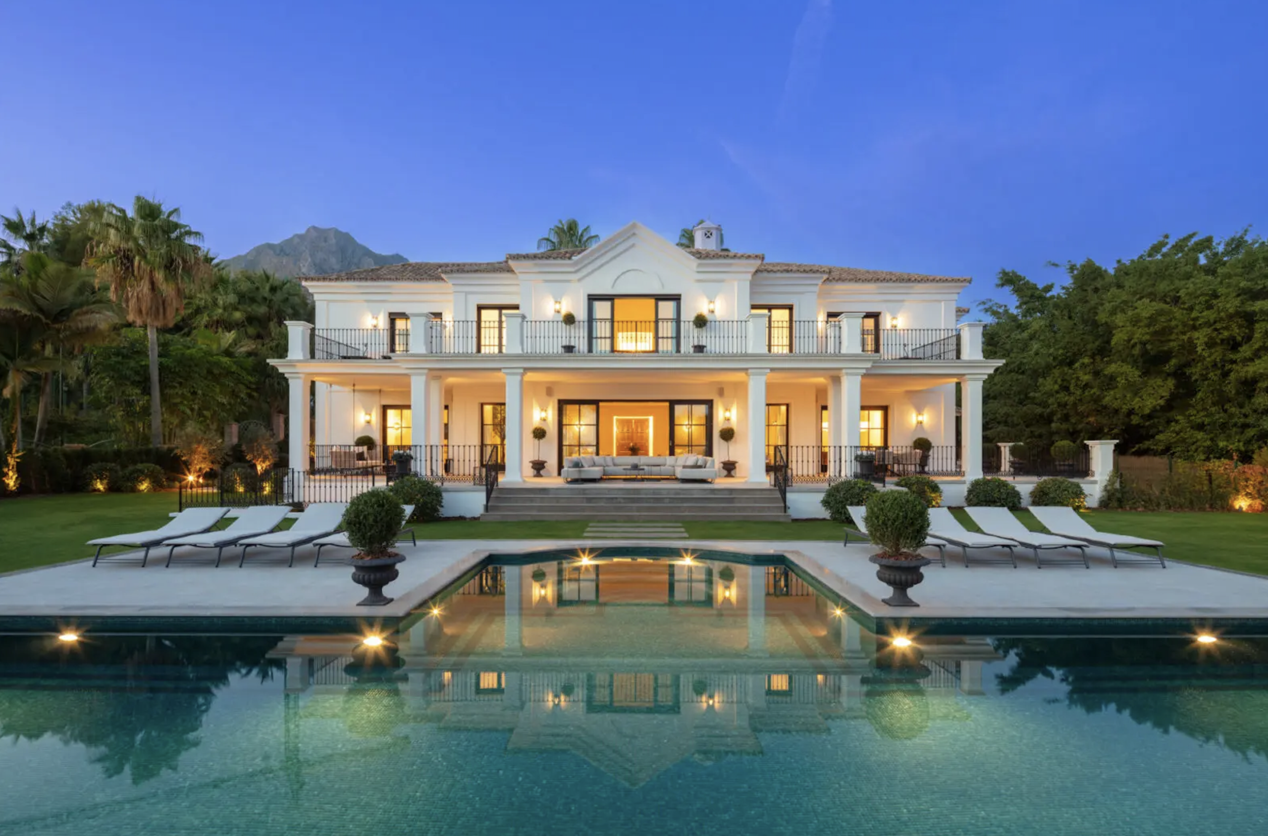 Marbella Old Quarter Andalusian townhouse interior with exposed whitewashed stone walls, timber truss ceiling, and contemporary glass staircase